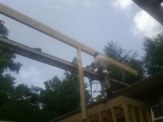 Carpenter setting a ridge beam over a new addition frame — Ice Dam Removal by Roofing Brothers in Jericho