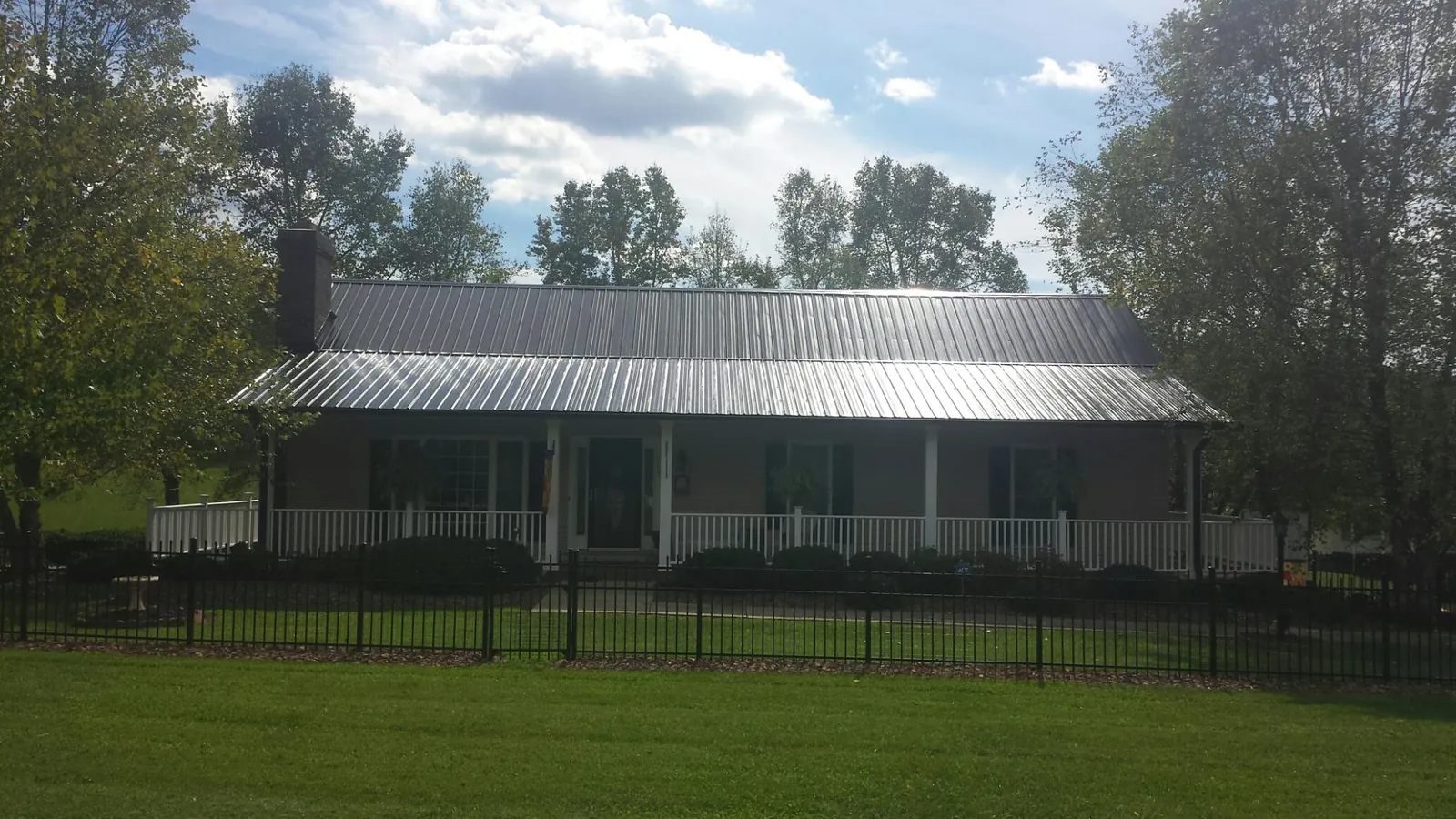 Gray metal roof on a brick ranch with a full width front porch — Gutter Guard Installation work by our crew in Jericho