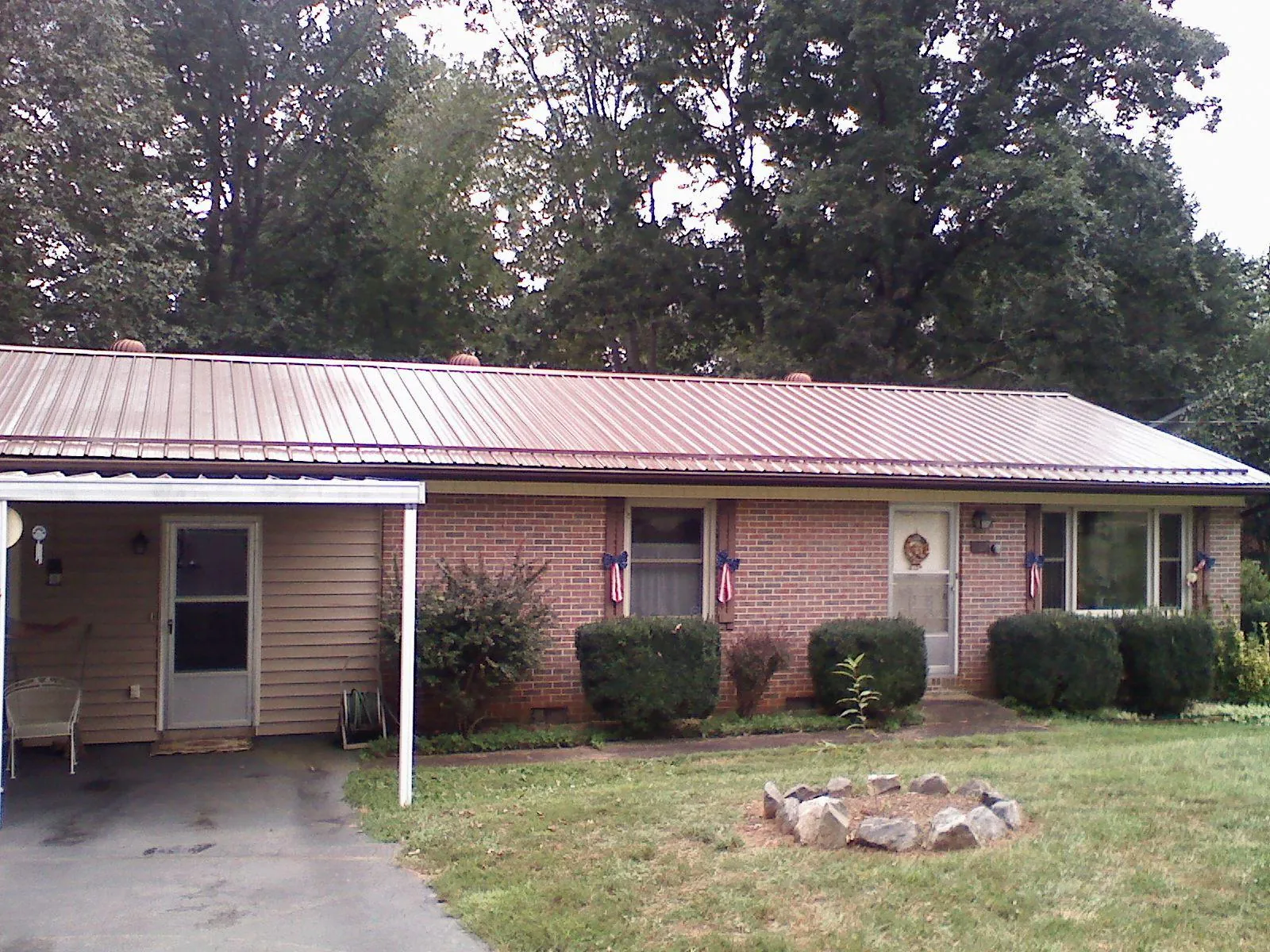 Bronze metal roof and carport on a brick ranch home — Roof Repair work by our crew in Jericho